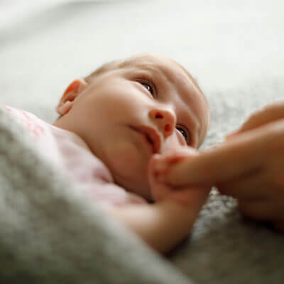 small baby holding on to moms finger