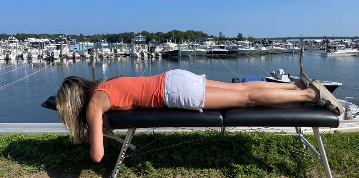 woman on adjusting table with boats in background