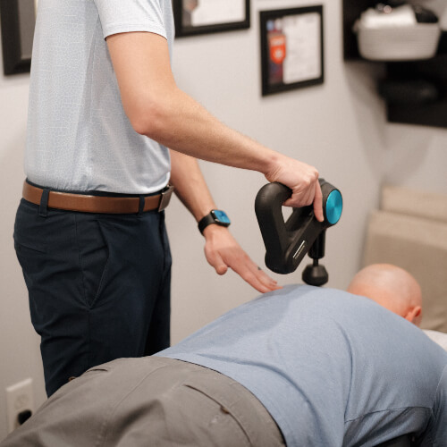Chiropractor using tool to treat a patient
