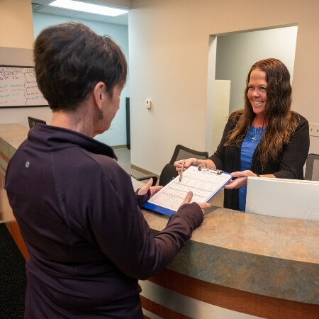 Receptionist handing over paperwork to patient