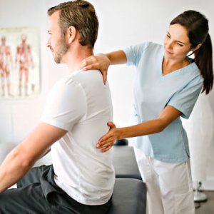 female chiropractor adjusting back of man sitting on table