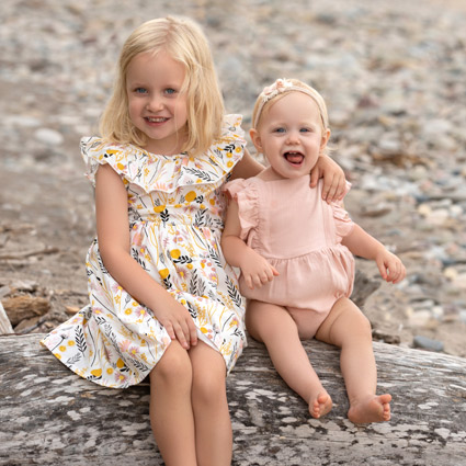 two little girls sitting on log smiling