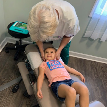 Dr. Amy gently adjusting little girls neck