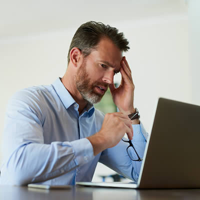 man with headache in front of computer
