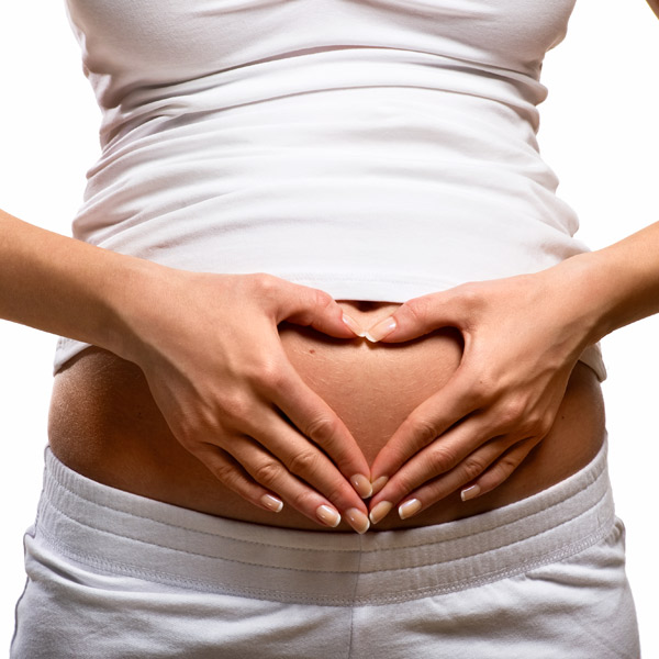 A pregnant woman holding her hands on her belly in the shape of a heart