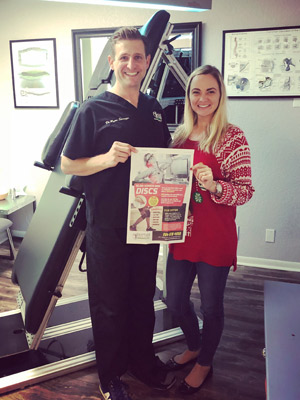 Two chiropractic doctors holding up a newspaper clipping