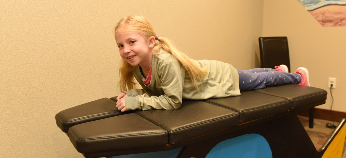 A girl on an adjustment table smiling