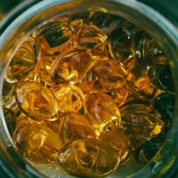 Close-up top view of transparent golden capsules inside an open jar, showcasing healthy supplements.