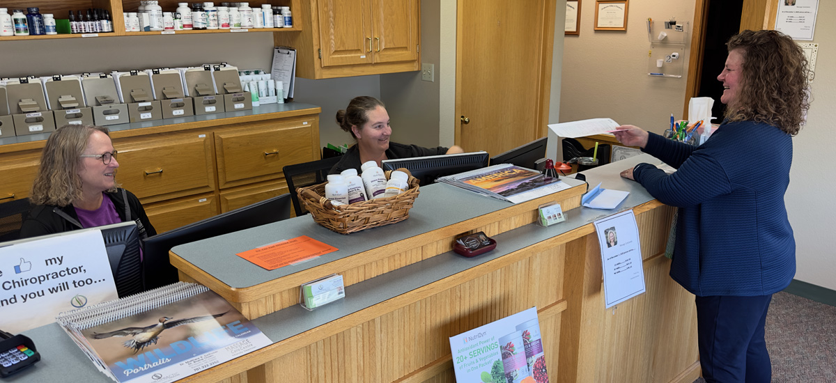 A smiling new patient standing at the reception desk.