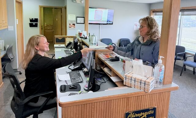 A smiling new patient standing at the reception desk.