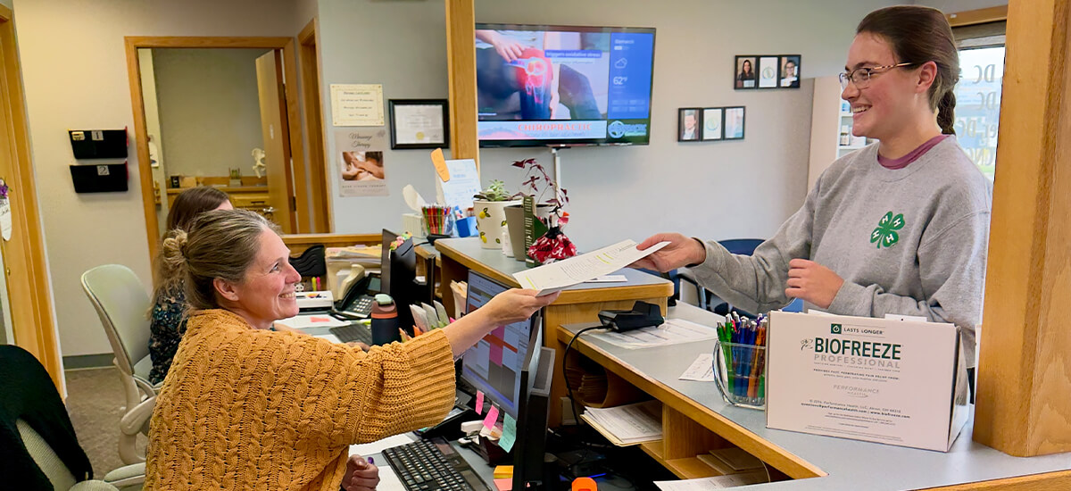 A smiling new patient standing at the reception desk.