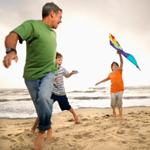 Father and sons running on the beach barefoot. 