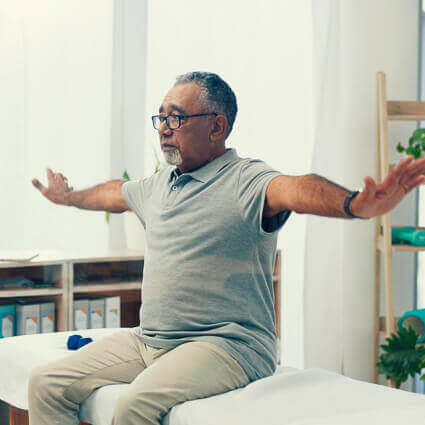 man-in-grey-shirt-with-glasses-raising-arms-to-sides-sq