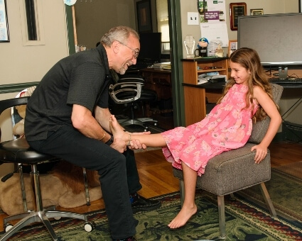 Chiropractor adjusting pediatric patient's leg