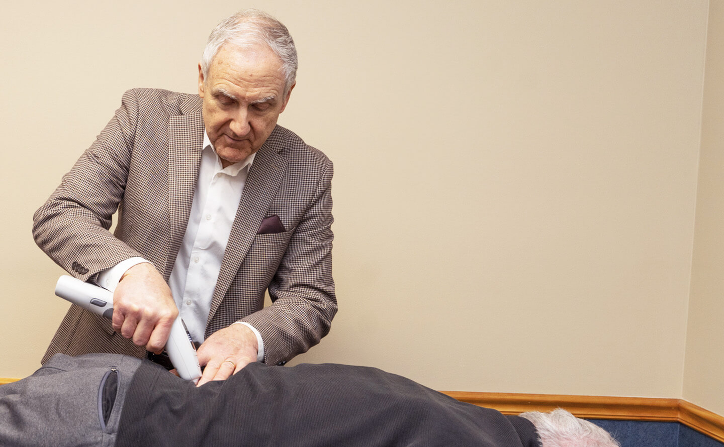 Dr. Bennett adjusting patient using chiropractic instrument