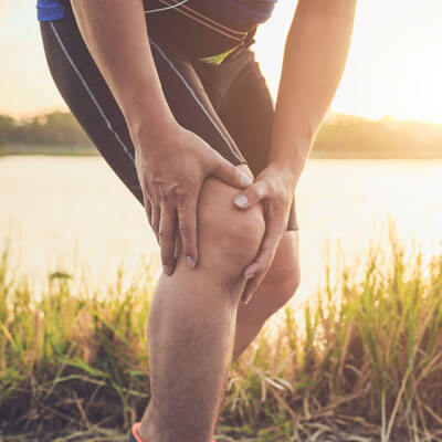 man holding his knee in pain while running