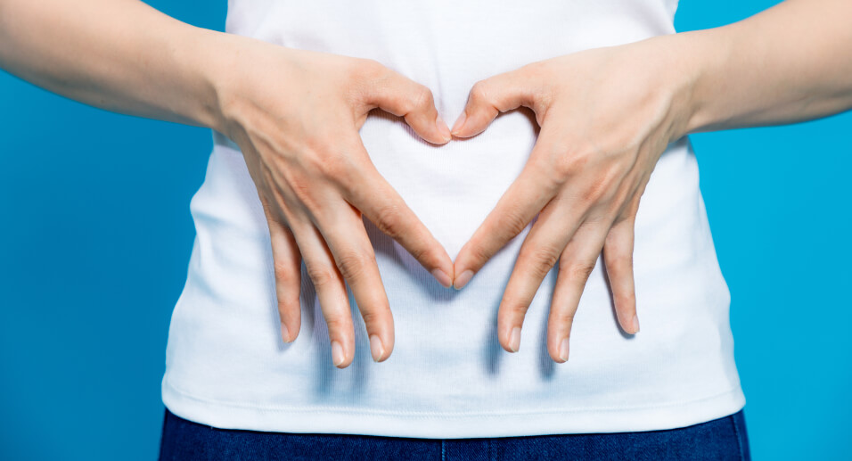 Woman making heart with hands on stomach