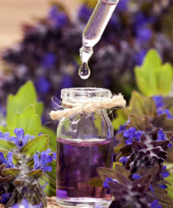 Essential oil in eyedropper, bottle, surrounded by flowers