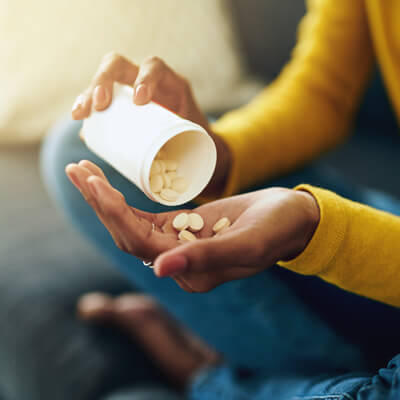 person pouring supplement pills in to their hand