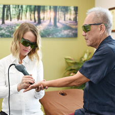 Dr Anna performing laser therapy on a patient's hand