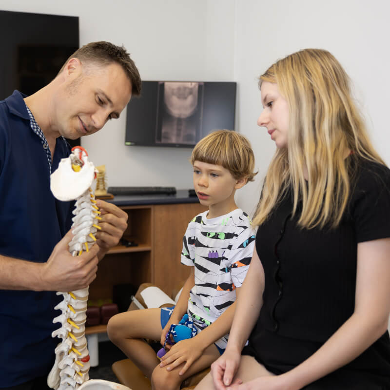 Dr showing spine model to mom and child