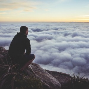 Man at the peak of mountain overlooking sea of clouds