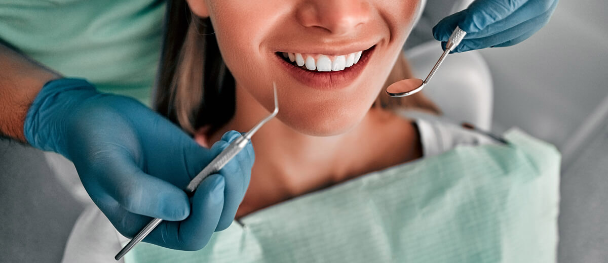 closeup of woman smiling and dentist hands