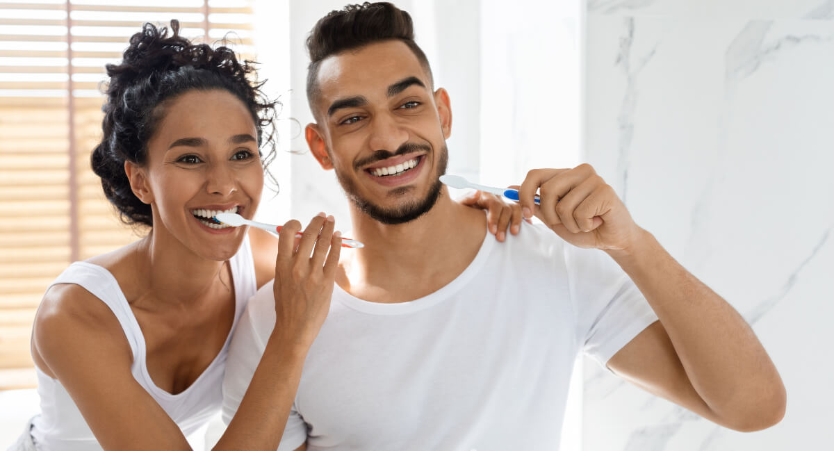 Smiling couple brushing their teeth