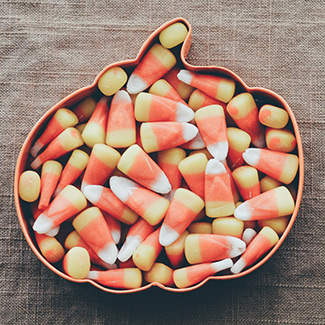 candy corn candy in a pumpkin-shaped bowl