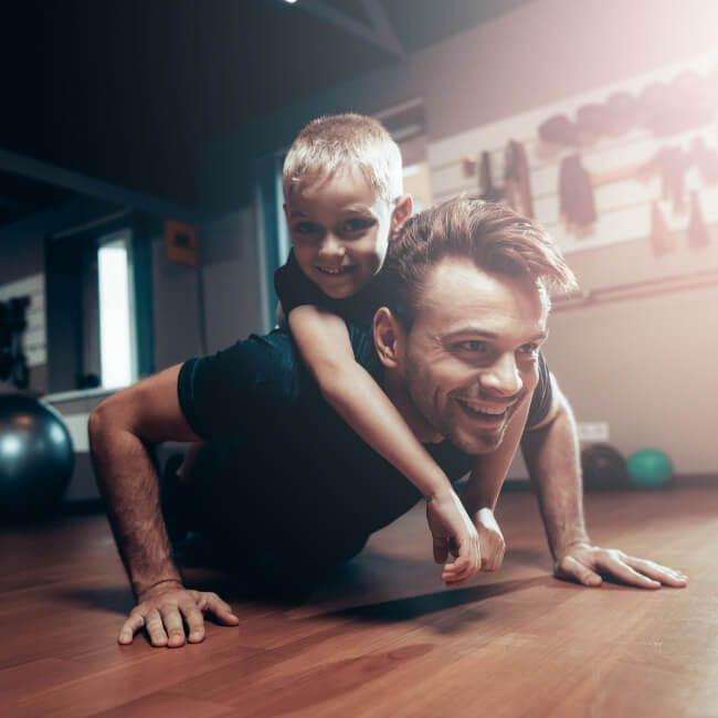 Man doing push-ups with his young son on his back
