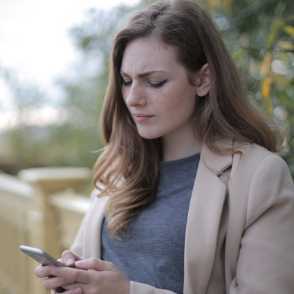 woman looking down at phone hard to read message