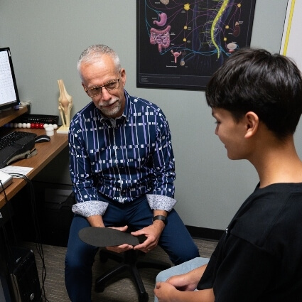 Steinbach chiropractor Dr Trevor showing patient a custom orthotic