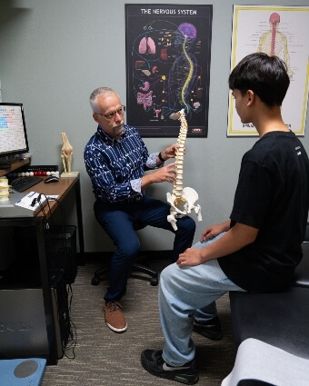 Steinbach chiropractor Dr. Trevor discussing spine model with patient