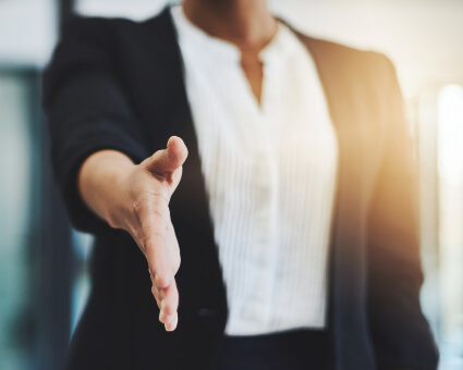 Business professional reaching out to shake hands