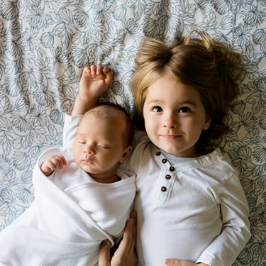 infant and little girl lying on bed