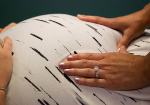 Patient and Doctor's hands cradling pregnant woman's belly