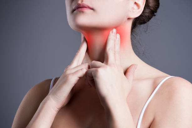 Sore throat, woman with pain in neck, gray background, studio shot