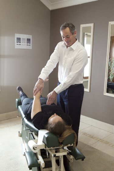Dr Marcus Chacos adjusting a client, relieving arthritis, sciatic and back pain through wellness care chiropractic adjustment Canberra Queanbeyan