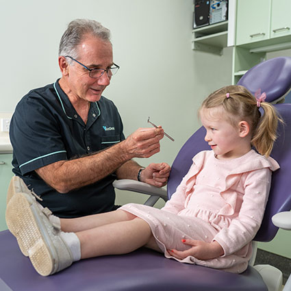 dentist showing little girl dental tool