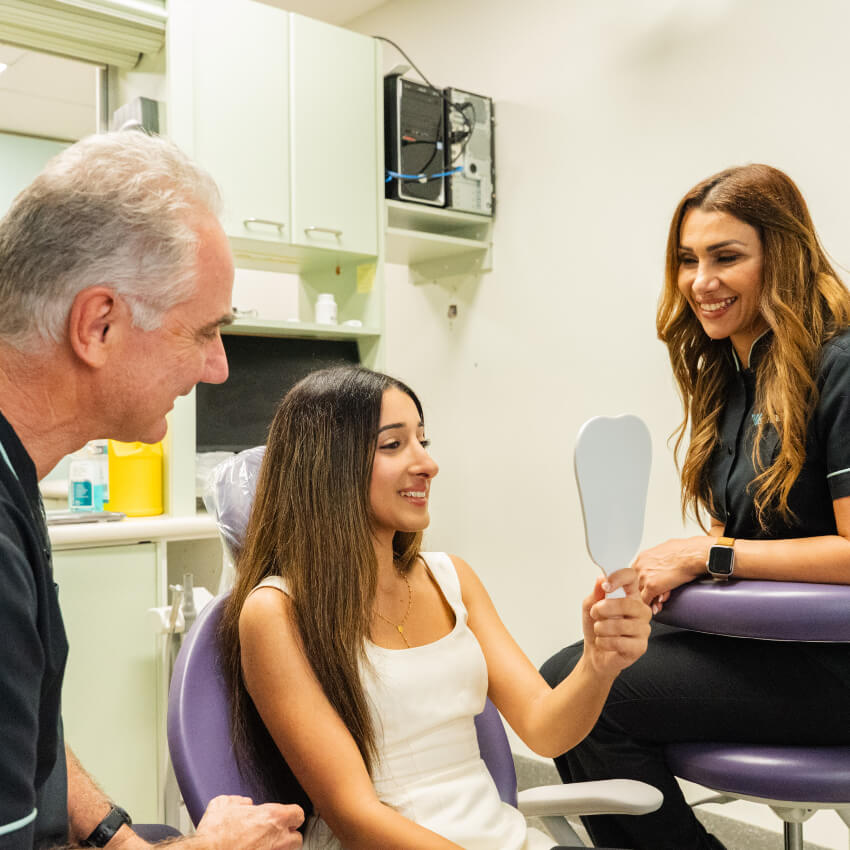 smiling patient looking into hand mirror