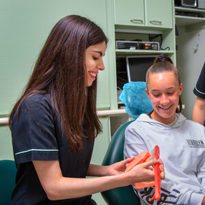 Dental hygienist demonstrating brushing technique to young patient