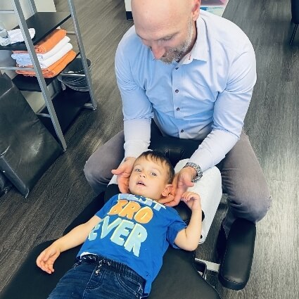 child having neck adjusted by Dr Tuzzolino
