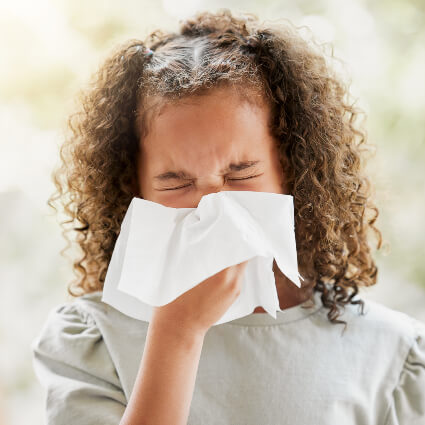 girl sneezing into tissue