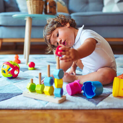 young boy stacks wooden toys