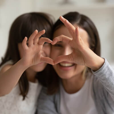 Mom and girl making heart with hands