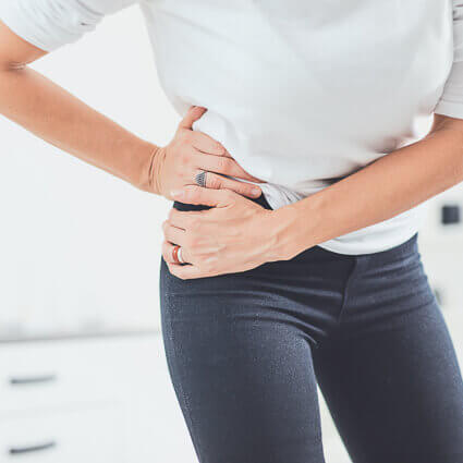 woman standing holding hip in pain
