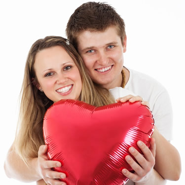 Couple hugging and holding red heart balloon