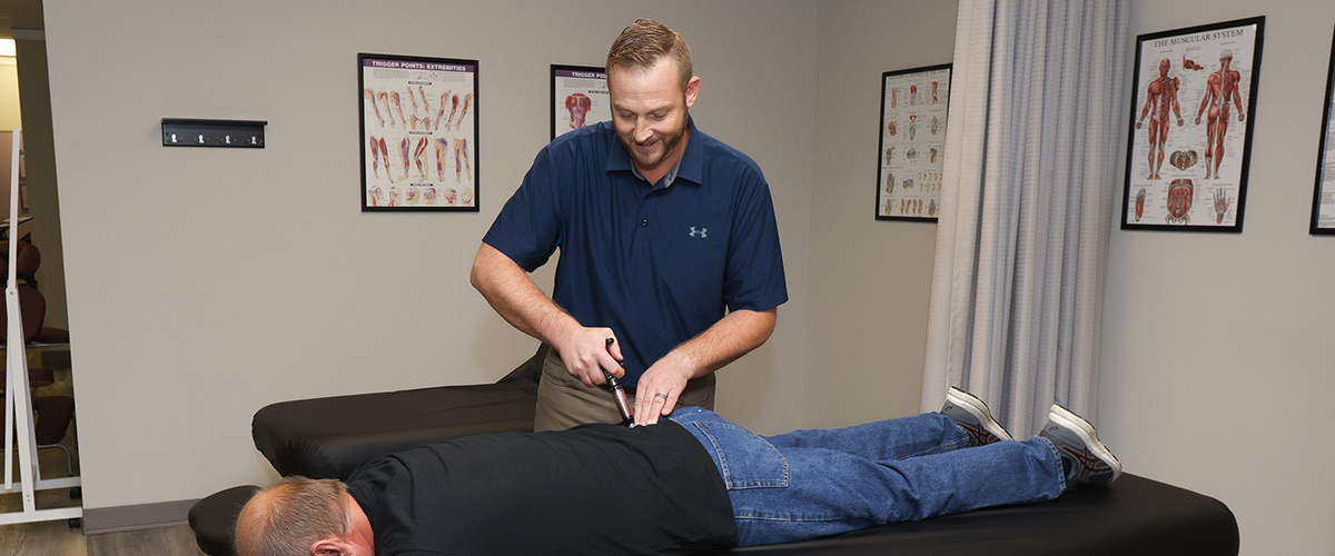 chiropractor using adjusting tool on patient