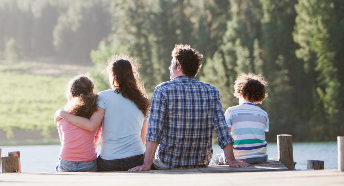 Family sitting at a peer looking at water