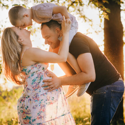 Pregnant mom embraced by husband and young child